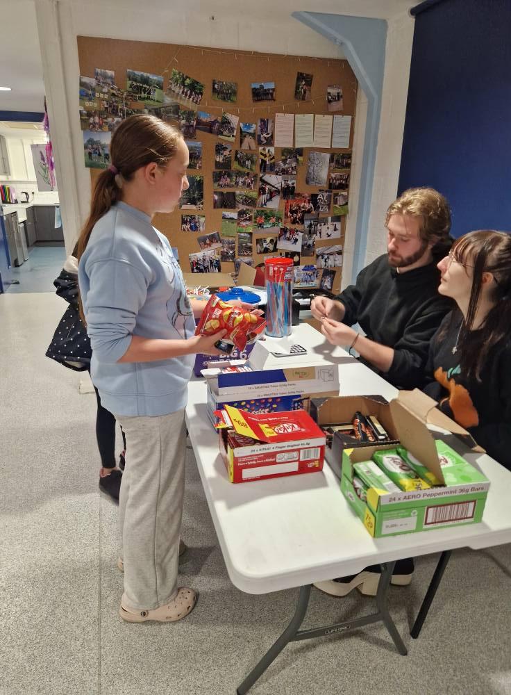 A young person taking part in a table craft activity with staff support.